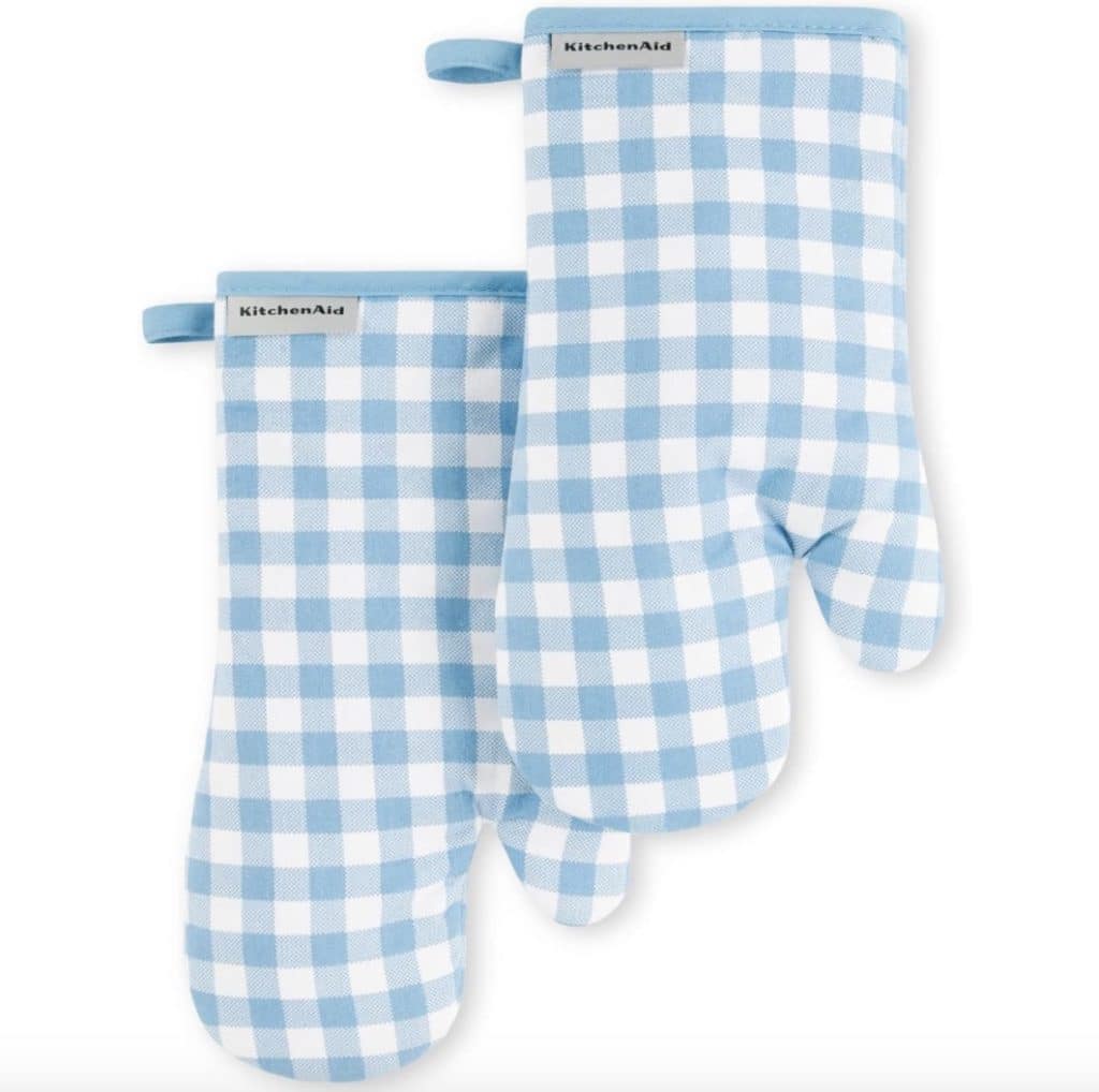 Two blue and white checkered oven mitts with hanging loops are laid flat, perfect for safely handling your next baked apple fritter recipe. Each mitt features a KitchenAid label at the opening, showcasing a classic gingham style.